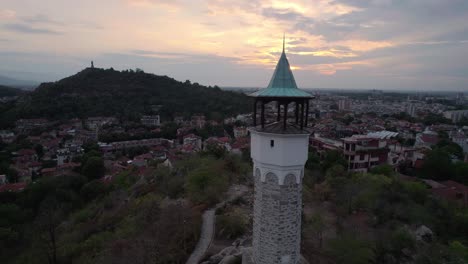 Aerial-View-Of-Clock-Tower-In-Plovdiv-Old-town-With-Sunset-Skies-Overhead