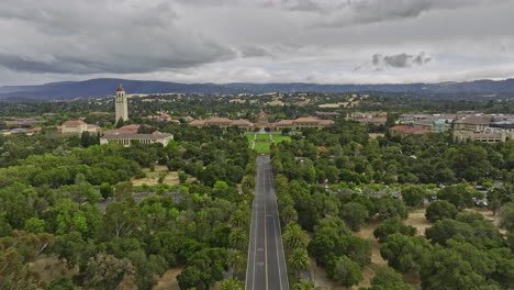 Stanford-City-California-Aerial-v8-establishing-low-level-flying-straight-above-palm-drive,-flyover-entrance-oval-lawn-and-main-building-of-the-university-campus---Shot-with-Mavic-3-Cine---June-2022