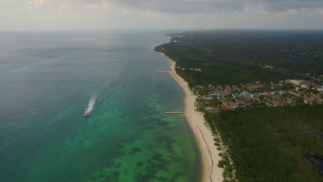Landscape-aerial-view-of-the-beach-in-Isla-Cozumel,-México-with-a-boat-navigating-near-the-shore