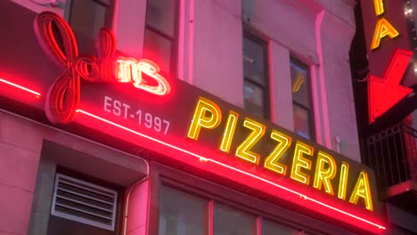 Neon-lit-Store-Sign-At-The-Entrance-Of-John's-Pizzeria-At-Night-In-New-York-City,-New-York