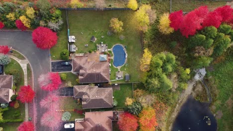 Drone-flying-over-city-suburbs-with-private-houses-and-colorful-gardens-on-sunny-day