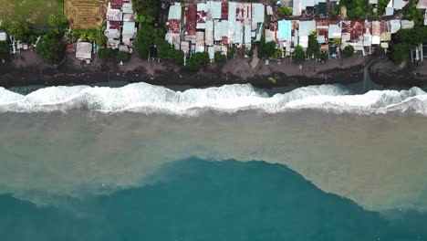 Foamy-Waves-Onto-The-Shore-With-Coastal-Town-In-Bali,-Indonesia