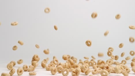 Whole-grain-cheerio-cereal-bouncing-into-pile-on-white-table-top-in-slow-motion
