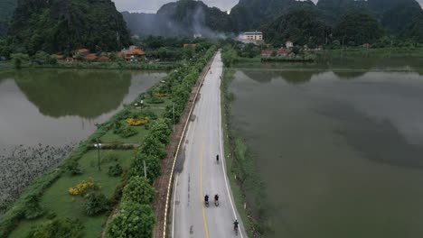 Cool-aerial-shot-following-people-on-bikes-on-a-asian-road-sounded-my-water-and-stunning-green-mountains