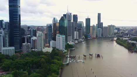 Aerial-view-drone-flyover-Brisbane-river-capturing-riverside-downtown-cityscape,-high-rise-buildings-and-skyscraper-in-central-business-district,-capital-city-of-Queensland,-Australia