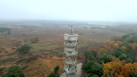 Aerial-footage-of-a-fire-watchtower,-a-man-is-enjoying-the-view-on-a-cold-autumn-day