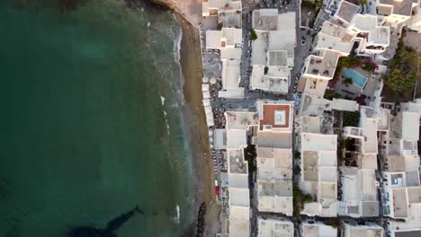 Vista-Aérea-De-Arriba-Hacia-Abajo-De-La-Playa-Y-Los-Edificios-Frente-Al-Mar-En-La-Isla-De-Paros,-Grecia