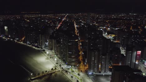 Aerial-view-of-illuminated-beaches-and-buildings-on-coast-of-Sao-Vicente,-Brazil