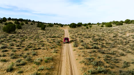 Aerial-Follow-Red-Jeep-Wrangler-Driving-On-Dirt-Road-Towards-White-Pocket-In-Utah,-USA