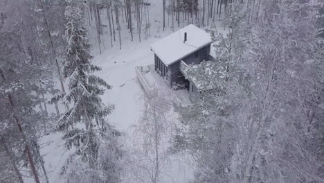 Winter-hut-in-the-middle-of-snow-forest,-bird's-eye-view