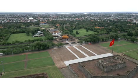 Drone-shot-of-vietnamese-flag-waving-in-the-lush-greenery-of-Hué,-Imperial-City