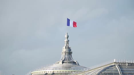 Bandera-Francesa-En-La-Arquitectura-Histórica-De-La-Cúpula-Ondeando-Contra-El-Cielo-Despejado-En-París,-Francia
