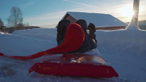 Pov-shot-of-happy-boy-on-sledding-downhill-snowy-mountains-in-Norway-during-sunset---Spinning-around-with-sled