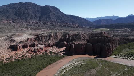 Ancient-Rock-Solid-Formation-into-Vineyards,-Cafayate-Route-in-Salta-Argentina,-Aerial-Drone-Fly-above-Mountain-Range-route-into-Subtropical-Forest,-Calchaqui-Valley
