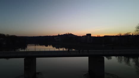 Hiker-walking-a-bridge-over-a-river-at-sunset-in-Passau-Germany