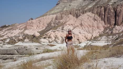 Blonde-girl-walking-in-the-red-valley-of-Cappadocia,-Turkey