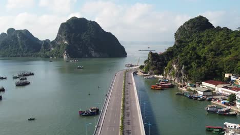 Drone-flyover-Viaduct-towards-Halong-bay-with-small-fishing-port,-Vietnam