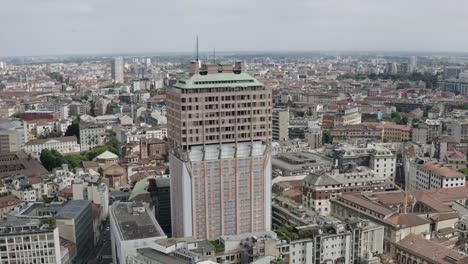 Torre-Velasca-tower-surrounded-by-Milan-cityscape,-aerial-view