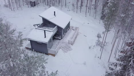 Remote-Rural-Winter-cabin-in-the-middle-of-forest-landscape-in-Finland,-drone-shot