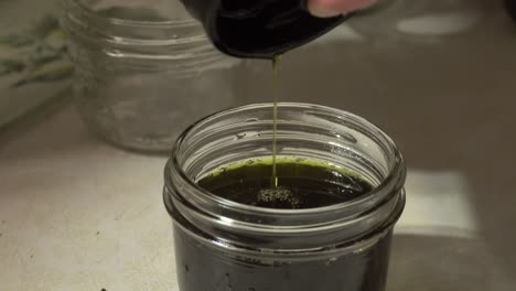 Pouring-green-liquid-from-french-press-into-glass-mason-jar