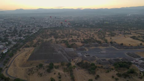 Filmische-Luftaufnahme-Von-Heißluftballons,-Die-Bei-Sonnenaufgang-über-Die-Alte-Pyramide-Im-Nebel-Gegen-Den-Himmel-Fliegen