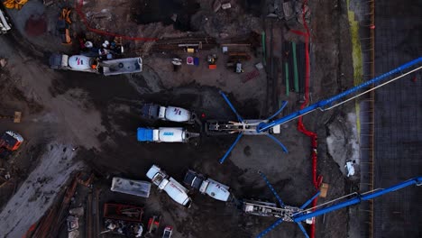 Aerial-view-above-cement-mixers-filling-concrete-pumps-at-a-construction-site-in-Brooklyn,-NY---top-down,-drone-shot