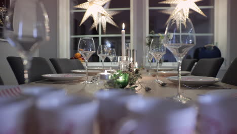 Christmas-dinner,-empty-table-with-wine-glasses,-candles-and-xmas-light,-closeup