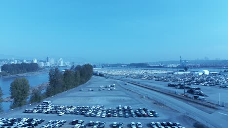car-lot-storage-aerial-flyover-Mitchell-Island-Fraser-River-freighters-dock-to-export-and-import-vehicles-on-sunny-summer-day-at-commercial-secure-property-JK-Japanese-used-and-new-auto-off-Knight-st