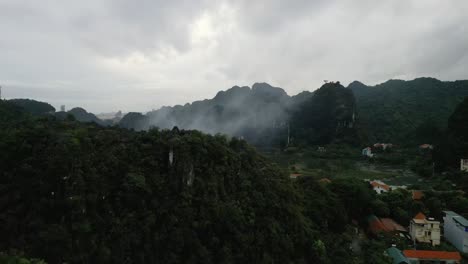 Aerial-flyover-of-the-green-and-lush-natural-village-in-Nin-Bihn,-Vietnam-in-high-altitudes-and-cloudy-forest