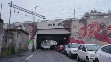 Cars-parked-under-railway-bridge-in-suburbs-of-Milan,-handheld-view