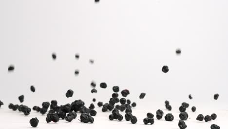 Freeze-dried-blueberries-bouncing-onto-white-table-top-in-slow-motion