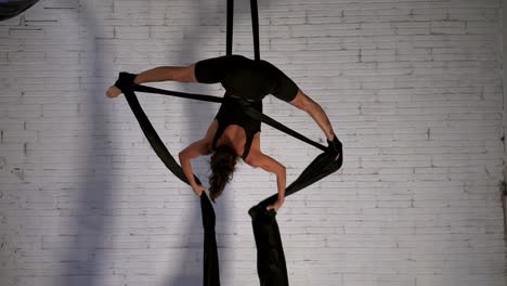 Female-dancer-doing-an-aerial-dance-performance-while-hanging-upside-down,-front-view