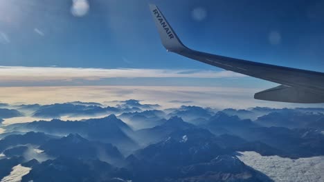 Ryanair-flying-above-majestic-Alps,-plane-window-view-with-wing