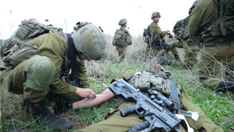 IDF-combat-medic-give-first-aid-to-wounded-infantry-soldier,-dolly-in