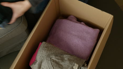 Woman-packing-folded-clothes-into-cardboard-box-selling-clothing-online-store-sale