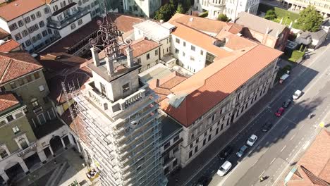 Clock-tower-being-repaired-in-downtown-Bergamo,-aerial-orbit-view