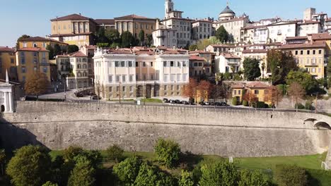 Stone-wall-and-Bergamo-Citta-Alta,-aerial-fly-backward-view