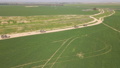 Aerial-View-Of-Four-Military-Armored-Humvee-Vehicles-of-IDF-Israeli-Golani-Infantry-Brigade-Driving-on-Dirt-Road-in-Rural-Green-Field