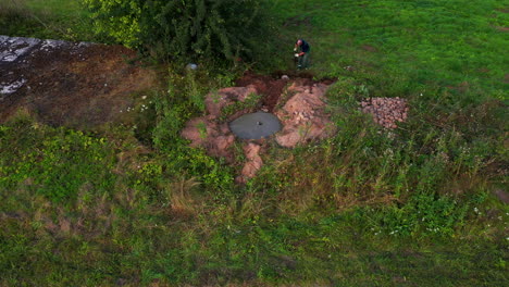 Man-digging-ground-with-shovel-in-rural-area,-aerial-view