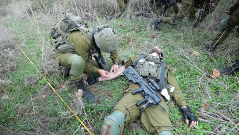 Médico-Del-Ejército-Israelí-Dando-Primeros-Auxilios-Inyectando-Una-Aguja-En-La-Vena-De-Un-Soldado-Herido-En-El-Campo-De-Batalla