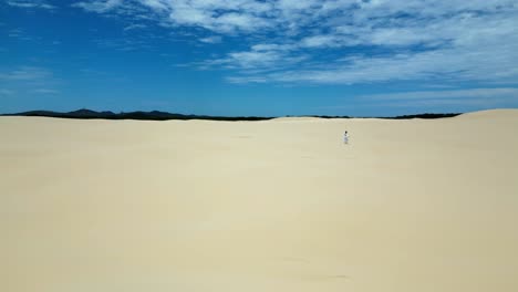 Girl-in-a-white-dress-is-first-walking-along-the-sand-dunes-and-starts-running-after-a-while