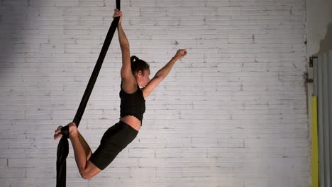 Aerial-yoga-instructor-starting-the-exercise-routine-while-wearing-black-sportswear,-fit-woman