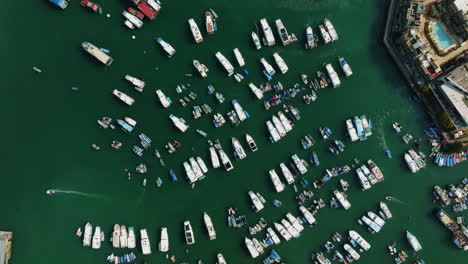 Drone-top-shot-of-bustling-harbor-with-boats-and-turquoise-water-in-Hongkong