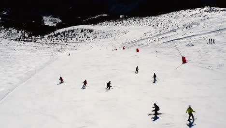 Aerial-view-of-people-skiing-down-a-steep-mountain-ski-slope,-on-a-sunny-winter-day,-in-Slovakia