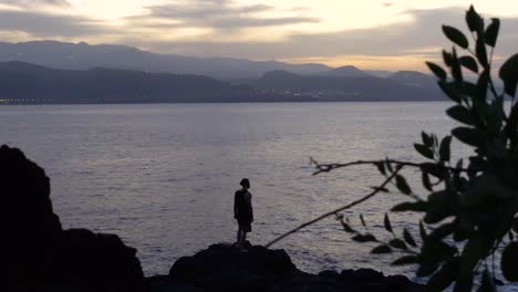 Young-man-watching-the-sunset-at-the-sea-on-a-cloudy-day-and-looking-into-the-distance-while-feeling-inspired