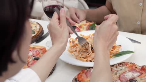 Amigos-Reunidos-Comiendo-Comida-Italiana-Juntos,-Gente-Irreconocible-Comiendo-Pasta-Tagliatelle-Y-Pizza
