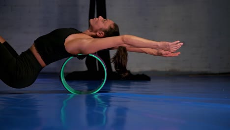 Woman-using-a-rolling-back-cylinder-to-stretch-her-back,-side-shot-of-person-stretching-out