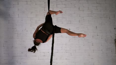 Woman-acrobat-practicing-acrobatic-stunts-in-the-air-while-hanging-upside-down,-still-shot