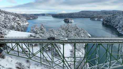 A-white-SUV-driving-across-Deception-Pass-bridge-while-snow-covers-the-ground