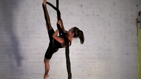 Aerial-dance-dancer-practicing-a-routine-while-hanging,-acrobat-woman-performing-stunt